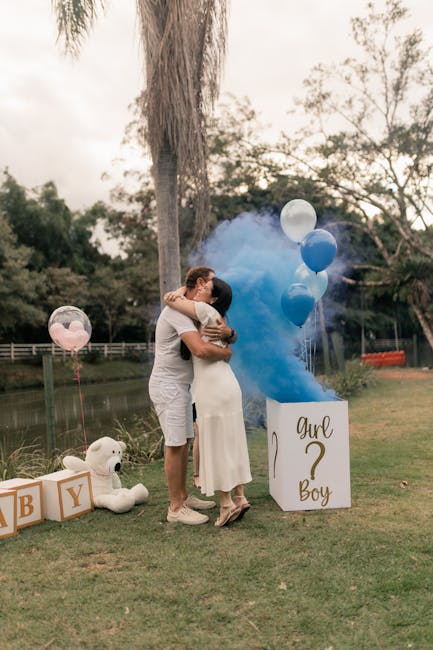 Couple embracing at outdoor gender reveal with blue smoke and balloons.