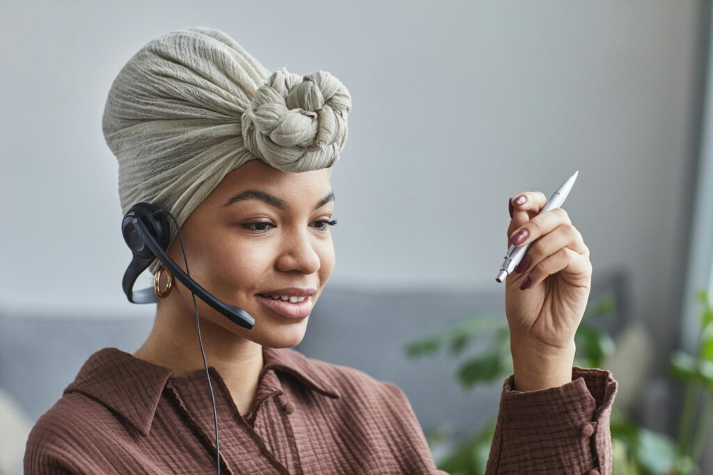 Smiling woman wearing a headset while working at a call center, looking engaged and professional symbolising contact us.