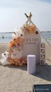 Beach-themed baby boy balloon arch with "Baby Boy" sign and white decorations for baby shower in Dubai.