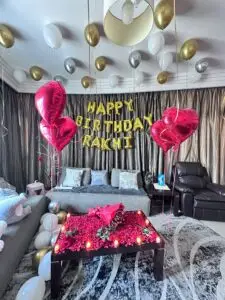 Pink and red balloon decoration with "Happy Birthday" and heart balloons in a bedroom setup for a birthday party in Dubai.