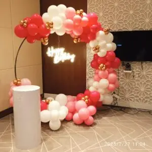 Pink and white balloon and floral decoration setup for event. Graceful pink and white themed decoration featuring balloons, flowers, and coordinated props. Ideal for birthday parties, baby showers, bridal showers, and other special occasions.