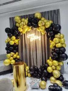 Black and gold balloon arch setup for event decoration.