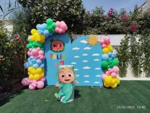 Cocomelon theme birthday party decoration with balloons and character props.