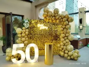 50th birthday decoration setup with golden balloons and themed backdrop.