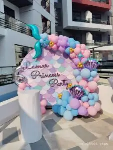 Mermaid birthday decoration with ocean theme balloons and seashell props.